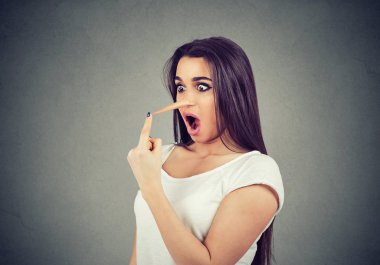 Yalancı kadın gri duvar arka plan üzerinde izole uzun burun duygu şok ile.