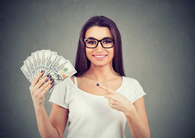 Casual giyim gri arka plan üzerinde izole para hayranı tutan mutlu bir kadın portresi