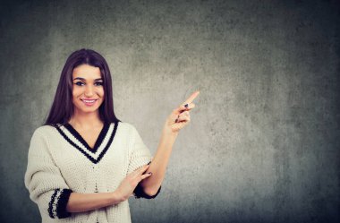 Bir kenara gri arka plan üzerinde izole kopya alanı üzerinde parmak işaret mutluluk ifade beyaz kazak giyen güzel bir kadın portresi 