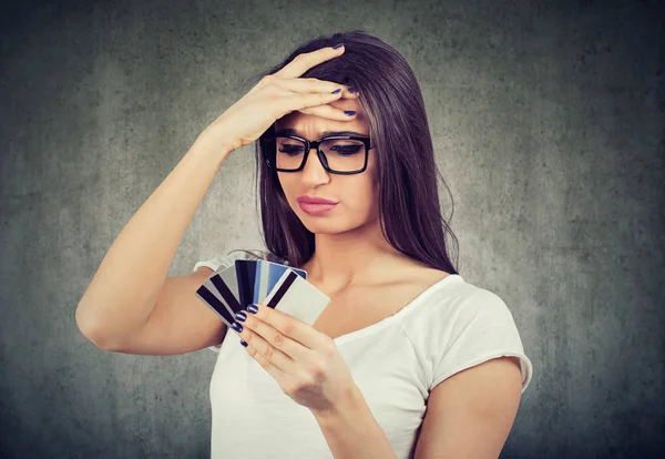 Mulher estressada olhando para muitos cartões de crédito cheios de dívida — Fotografia de Stock