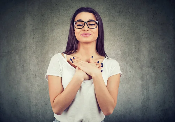 Mujer fiel con los ojos cerrados mantiene las manos en el pecho cerca del corazón, muestra bondad —  Fotos de Stock