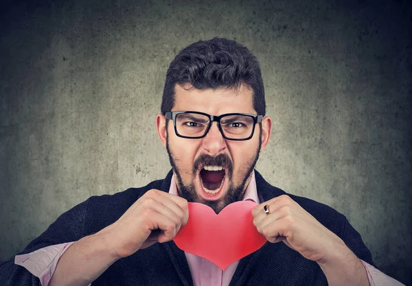 Homme frustré déchirant un cœur rouge — Photo