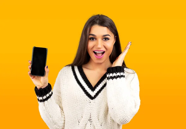 Verbaasd gelukkige vrouw in witte trui tonen een nieuwe smartphone — Stockfoto