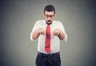 Şok işadamı inançsızlık içinde aşağı bakıyor, yerde parmakları ile işaret