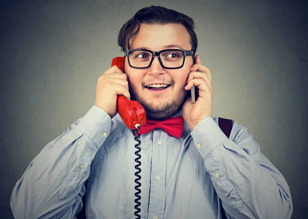 Счастливый бизнесмен, пользующийся мобильным телефоном и ретро-телефоном — стоковое фото