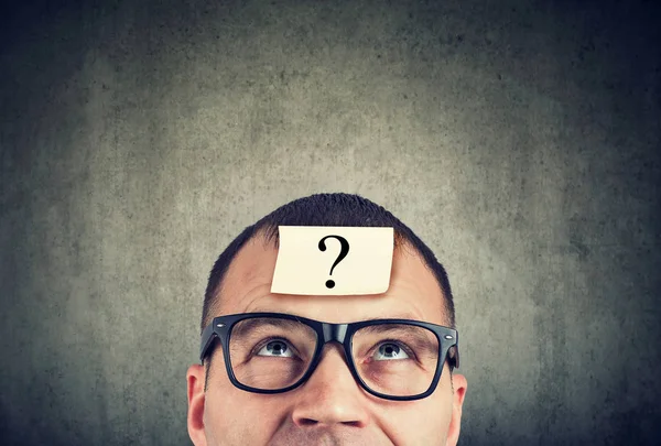 Homem de óculos com ponto de interrogação olhando para cima — Fotografia de Stock