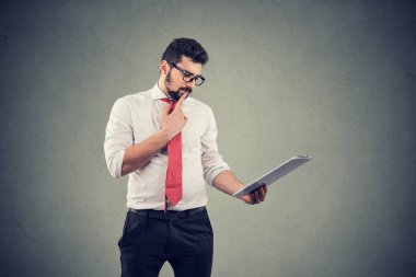 Düşünceli adam çene dokunmadan ve tablet bilgisayar kullanarak 