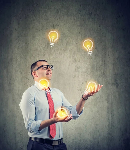 Young business man juggling with new ideas light bulbs — Stock Photo, Image