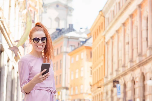 Beautiful woman standing on the street and using her mobile phone — Stock Photo, Image