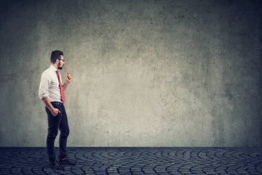 İş adamı duvarın önünde duruyor. 