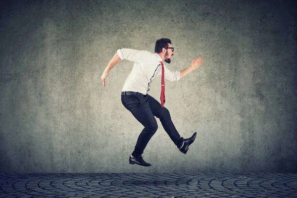 Jovem empresário correndo saltar contra fundo parede — Fotografia de Stock