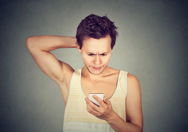 Joven mirando el teléfono móvil con expresión confusa en la cara —  Fotos de Stock