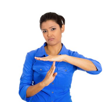 Portrait of a young serious woman showing a time out gesture with hands isolated on white background clipart