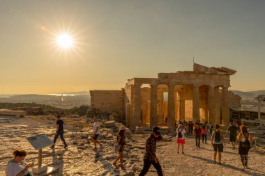Turistler Atina ve Yunanistan 'daki harabelerin mimari güzelliğini takdir ederken, Akropolis' te güneş parlıyor.
