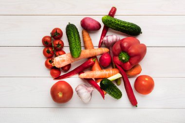 Beyaz ahşap arka planda çeşitli çiğ sebzeler ve boş alanlar. Kabak, salatalık, biber, mantar, domates, karnabahar, marul, havuç, kereviz, sarımsak, kırmızı biber.