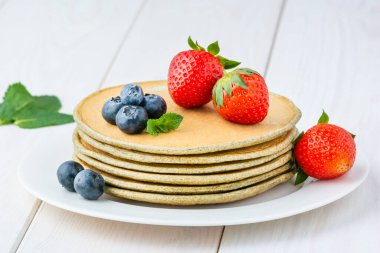 Bir tabakta, yabanmersinli, çilekli ve naneli kenevir unu krepleri..