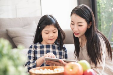 Tablet kullanan mutlu Asyalı aile, oyun oynamak için dizüstü bilgisayar film izlemek, yaşam tarzı konsepti için evde dinlenmek.