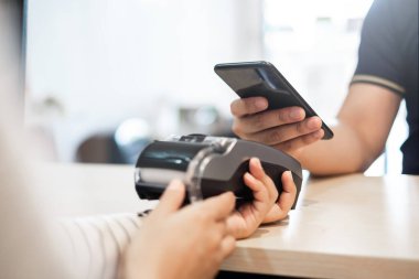 Müşteri, kafe restoranının sahibine ödeme yapmak için telefon, nakitsiz teknoloji ve kredi kartı ödeme konsepti kullanıyor.