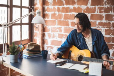 Gitarla şarkı yazan Asyalı müzisyen.