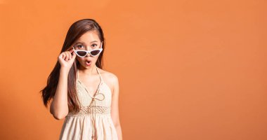 Yazlık mayo giymiş genç Asyalı kadın. Fotokopi çekilen turuncu arka planda mutlu gülümsüyor.