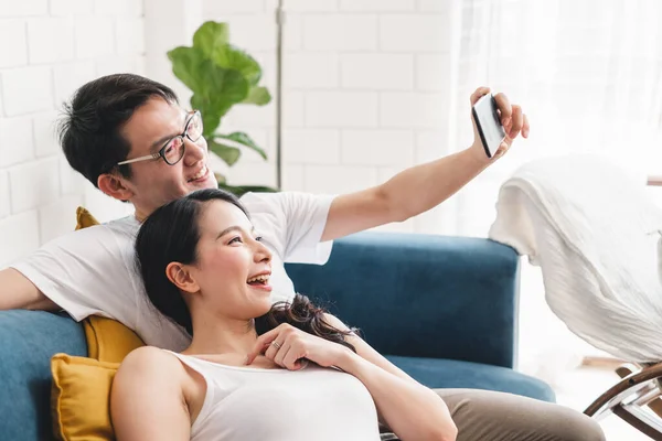 Young Asian couple lover taking selfie by mobile phone at home, relax and lifestyle at home concept