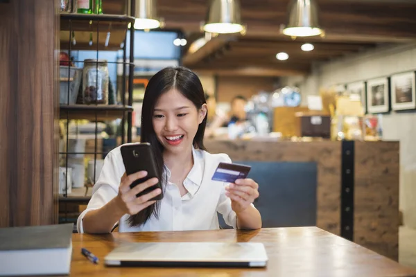 コーヒーショップカフェでオンラインショッピングのためのスマートフォンやクレジットカードを使用して若い美しいアジアの女性 — ストック写真