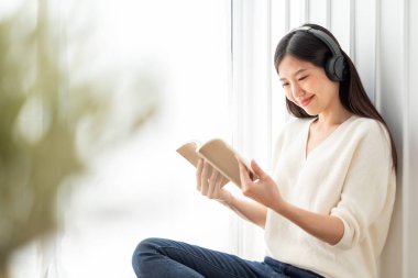 Genç ve güzel Asyalı kadın evde şarkı dinliyor, mutlu yaşam tarzı konsepti