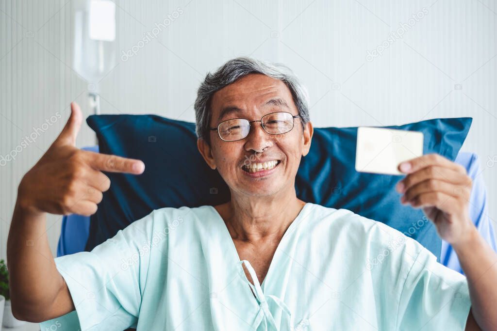 Old asian patient man showing credit card with happy and smile on patient bed