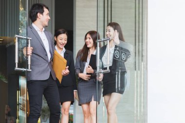 Asyalı iş adamları ofisteki meslektaşlarıyla yürüyüp konuşuyorlar