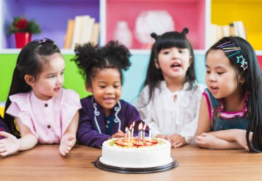 Grup çeşitliliği çocuklar doğum günü pastasını üflüyorlar.