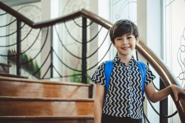 Okul çantasıyla yerde duran sevimli çocuk, fotokopi çekerek gülümsüyor.