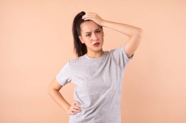 Genç Asyalı kadın kafasına dokunuyor. Baş ağrısı çekiyor.