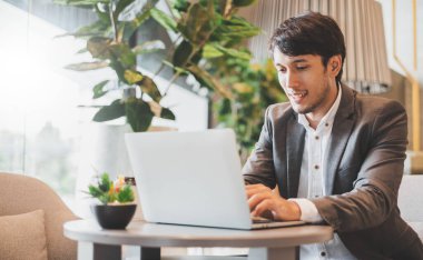 Asyalı işadamı ofiste çalışırken dizüstü bilgisayar kullanıyor