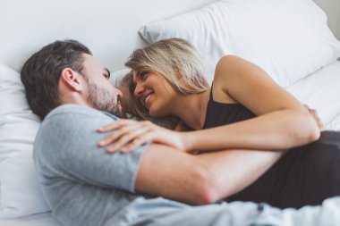 Mutlu çift yatakta, romantik zamanda sarılıp öpüşüyor, aşk ve tutkulu bir konsept..