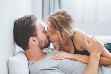 Mutlu çift yatakta, romantik zamanda sarılıp öpüşüyor, aşk ve tutkulu bir konsept..