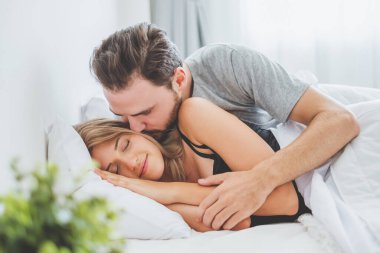 Mutlu çift yatakta, romantik zamanda sarılıp öpüşüyor, aşk ve tutkulu bir konsept..