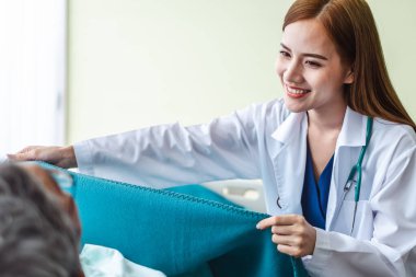 Asyalı doktor kadın ve hemşire hastanede yatan yaşlı adamla ilgileniyorlar, Asyalı tıbbi konsept.