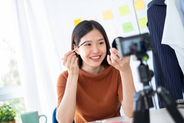 Asyalı kadın güzellik blogcusu / vlogger internet üzerinden canlı yayın yoluyla makyaj dersi veriyor