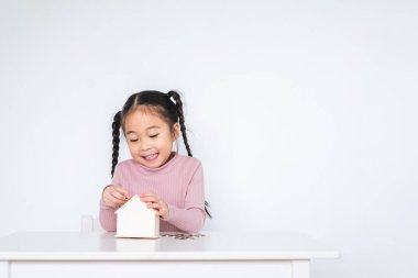 Asyalı kız çocuğu, kiralık kasaya para koy, para biriktirme kavramını beyaz arka planda tut.