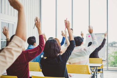 Bir grup iş adamı toplantı odası seminerinde konuşmacı ile aynı fikirde olmak için ellerini kaldırdı.