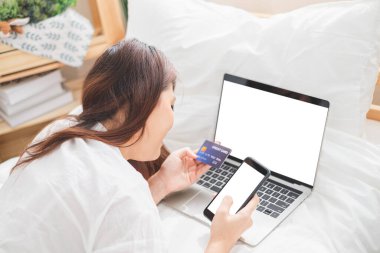 Güzel Asyalı kadın online alışveriş için laptop ve akıllı telefon kullanıyor, Asyalı kadın yaşam tarzı konsepti.