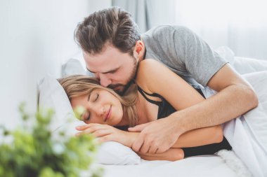 Mutlu çift yatakta, romantik zamanda sarılıp öpüşüyor, aşk ve tutkulu bir konsept..