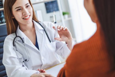 Asyalı doktor kadın elinde şırınga iğnesiyle Asyalı genç hasta kadın, Asyalı tıbbi konsept