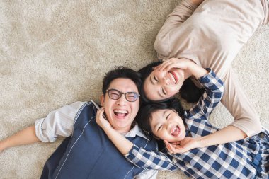 Mutlu Asyalı aile mutlu bir şekilde uzanıyor ve gülümsüyor.