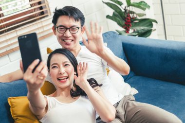 Genç Asyalı çift evde cep telefonuyla selfie çekiyor, ev konseptinde rahatlıyor ve yaşam tarzını geliştiriyor.