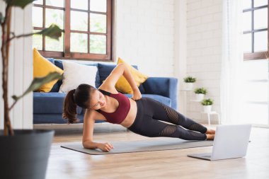 Genç Asyalı sağlıklı kadın antrenmanı evde, egzersiz, formda, yoga yapıyor, spor yapıyor.
