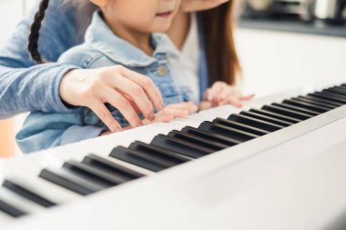 Asyalı genç piyanist öğretmen kız öğrenciye piyano çalmayı öğretiyor, müzik eğitimi konsepti