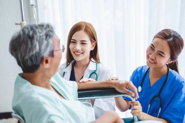 Asian doctor woman and nurse encourage disabled old man patient sitting on wheelchair at hospital, asian medical concept