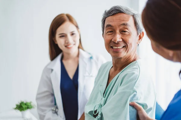 Asian doctor woman and nurse encourage disabled old man patient sitting on wheelchair at hospital, asian medical concept