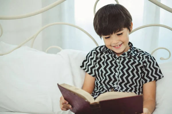 Çocuk Beyaz Yatakta Kitap Okuyor Gülümsüyor Mutlu Bir Hafta Sonu — Stok fotoğraf